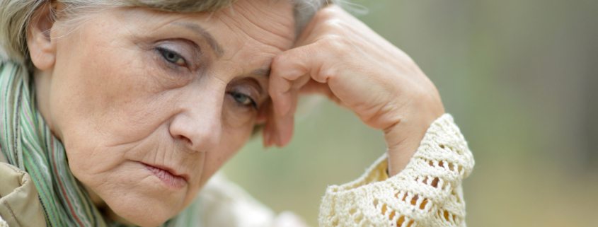 pensive elderly woman on the background of autumn leaves